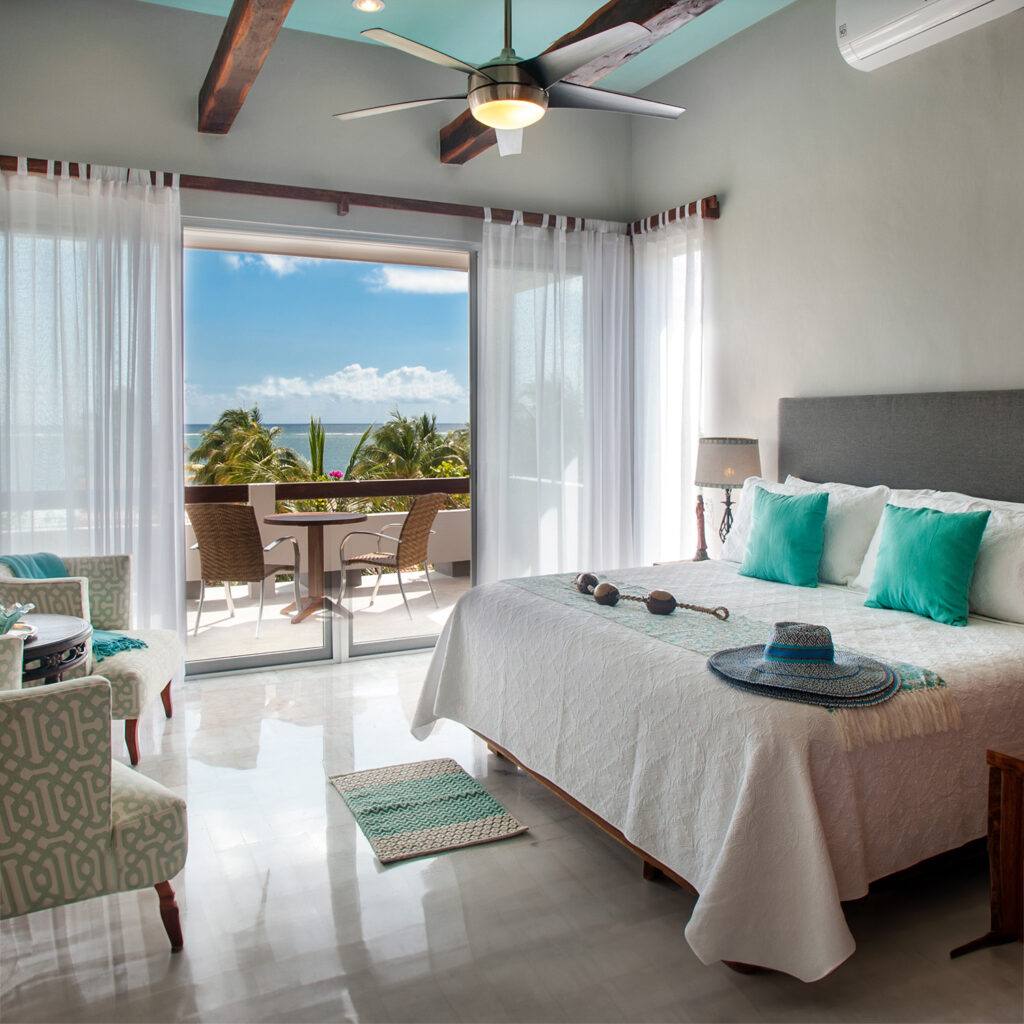 A bright and airy bedroom with a cozy bed, ocean view, and access to a private balcony.