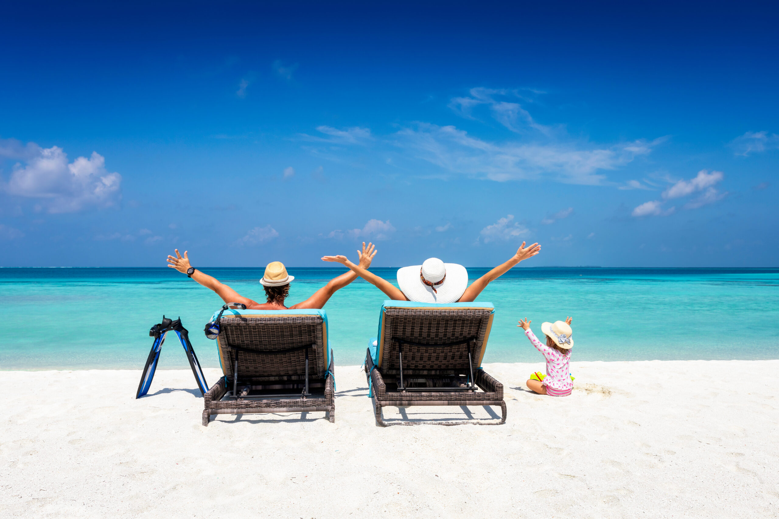 Happy family on sunbeds enjoys their vacation on a tropical beac