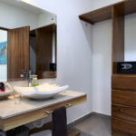 A modern bathroom with wooden cabinetry, a large mirror, and a stylish sink.