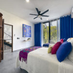 A colorful bedroom with bright decor, traditional Mexican art, and a large window.