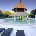 A large community pool with a thatched-roof palapa in the center.