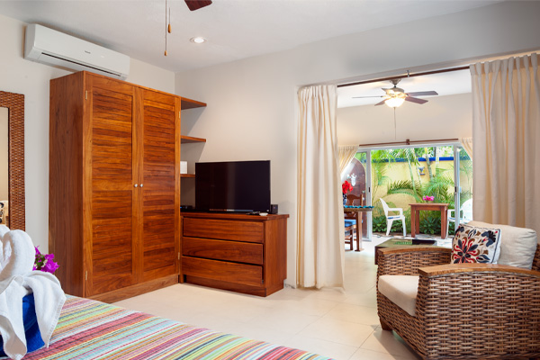 A cozy bedroom with wooden furniture, a TV, and sliding doors leading to a patio with outdoor seating.