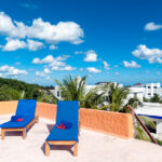 Rooftop lounge area with two blue loungers and an ocean view.