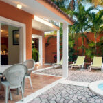 Patio area with a dining table and loungers by the pool.