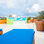 Rooftop seating area with colorful cushions and potted plants.