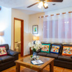 Living room with leather sofas and vibrant pillows, decorated with Mexican artwork.