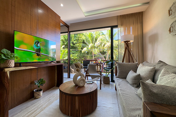 Modern living room with comfortable sofa, large TV, and view of tropical garden at Casa Alba.