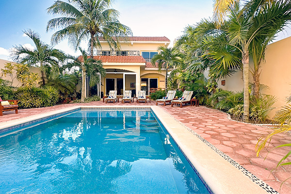 Large pool surrounded by tropical plants and lounge chairs at Casa Zarah.