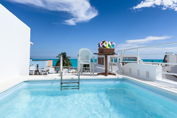 Rooftop pool with ocean views and seating area at Cuatro Estaciones.