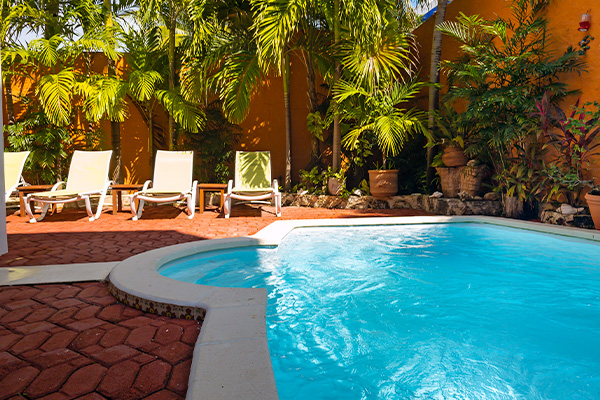 Private pool with lounge chairs and lush tropical plants.