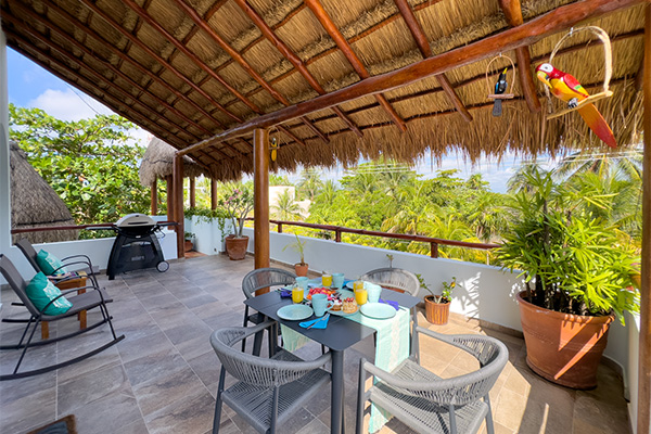 Rooftop terrace with dining table, rocking chairs, and tropical decor at Casa Sonoma Apartment #4.