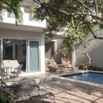 A private patio with lounge chairs, a small dining area, and a pool, surrounded by lush tropical plants at Casa Agua Azul.