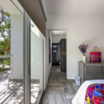 A bedroom with sliding glass doors leading to a balcony, featuring bright accents, a sleek dresser, and decorative touches.