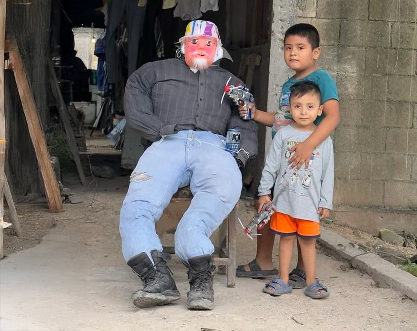 A heartwarming scene showing two children and an effigy of an old man, ready for the Año Viejo tradition in Mexico. This custom, often involving firecrackers and community gatherings, symbolizes the cleansing and renewal that comes with the New Year.