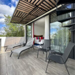 Spacious private balcony with lounge chairs, a wooden pergola, and a spiral staircase, offering a seamless indoor-outdoor experience with jungle views.