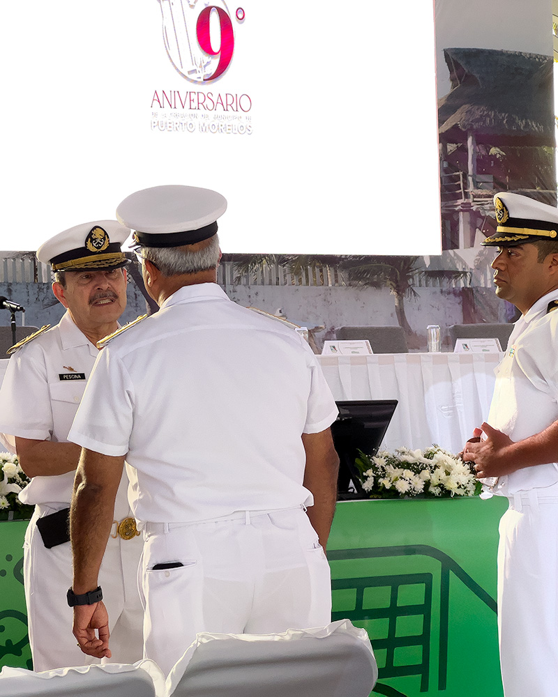 Naval officers in white uniforms conversing at the 9th-anniversary celebration of Puerto Morelos’ independence