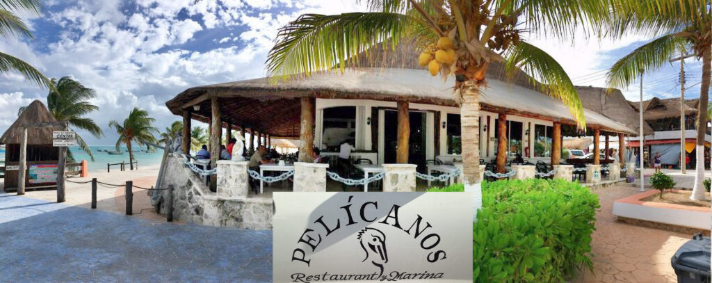 Outdoor view of Pelícanos Restaurant in Puerto Morelos, featuring its traditional thatched roof and open-air seating overlooking the Caribbean Sea.