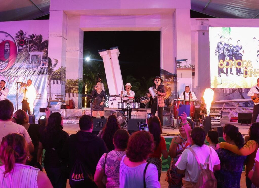 A lively performance by a band at Puerto Morelos’ 9th-anniversary celebration, with a crowd enjoying the music.