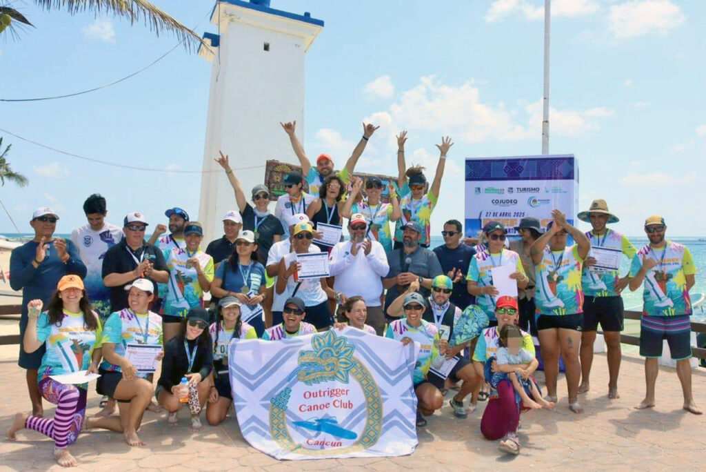 Group photo of smiling athletes from the Outrigger Canoe Club Cancun celebrating at the 1st Reef Race in Puerto Morelos.