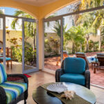 Casa Zarah screened porch with lounge chairs, garden view, and pool access.