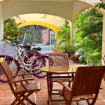 Casa Zarah outdoor patio with wooden dining set, pink-rimmed bikes, and lush tropical greenery.