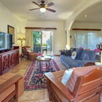 Spacious living room with carved wooden furniture, plush seating, and garden views through sliding glass doors.