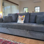 Close-up of gray sleeper sofa with colorful embroidered pillow in Casa Zarah’s living room.