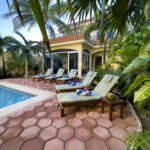 Casa Zarah poolside lounge chairs surrounded by tropical plants and palm trees.