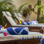 Casa Zarah striped pool loungers with blue rolled towels and coconuts, surrounded by tropical plants.