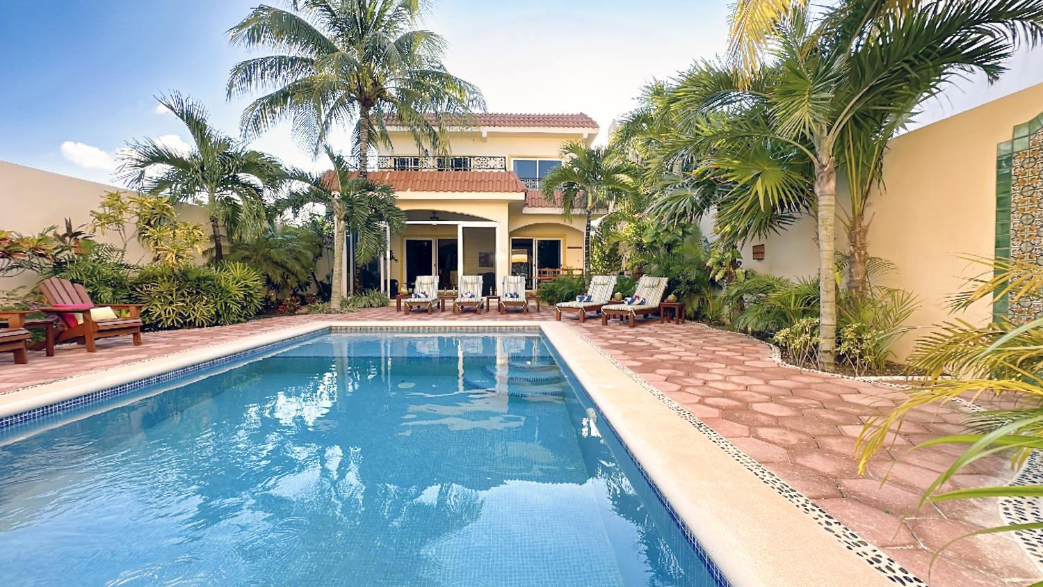 Casa Zarah private pool surrounded by palm trees, lounge chairs, and tropical landscaping.