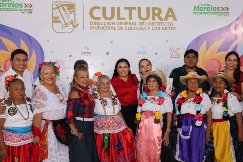 Group of local artists, performers, and officials in traditional and festive clothing at the Mosaico Cultural event in Leona Vicario, standing in front of a banner for the Municipal Institute of Culture and the Arts.