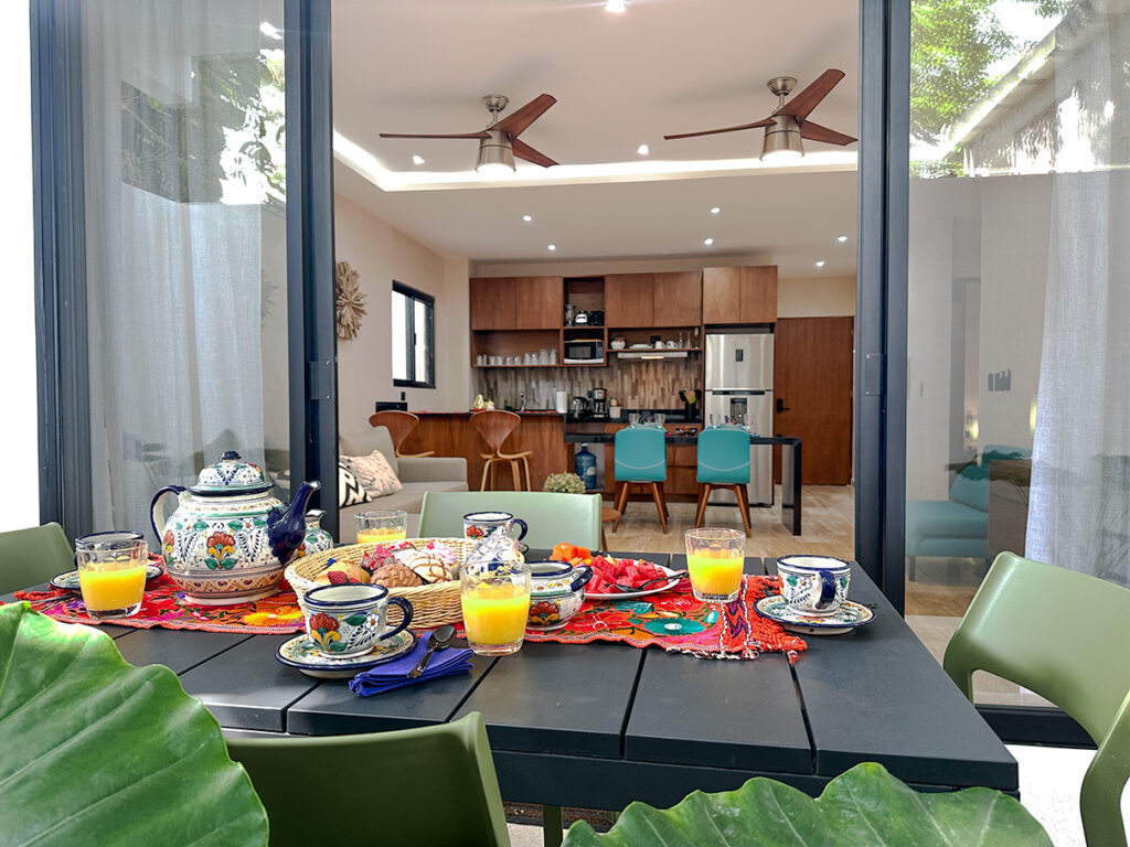 Casa Daniela patio table set for breakfast with view into modern kitchen and dining area.