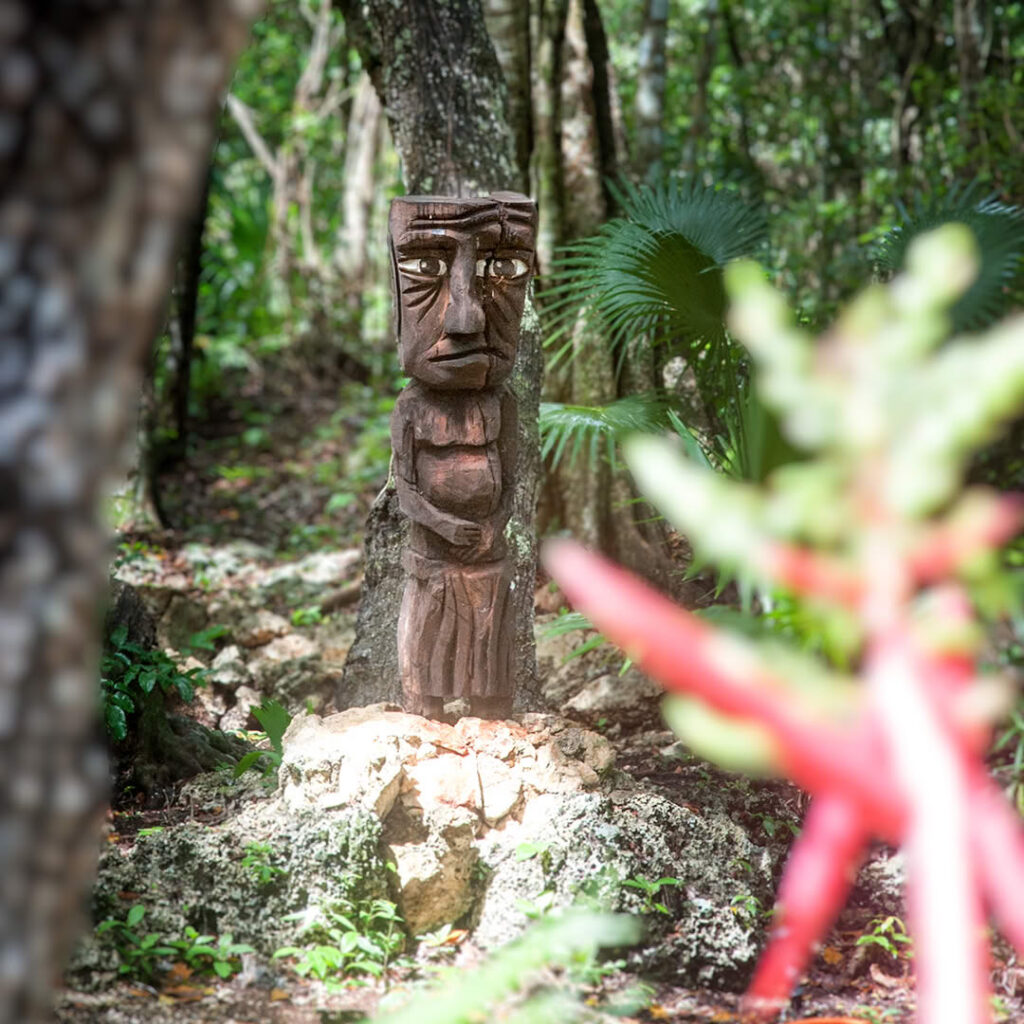 Carved wooden figure standing among trees in the jungle