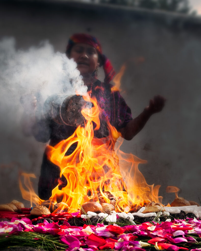 Maya woman performing fire ceremony with smoke and petals