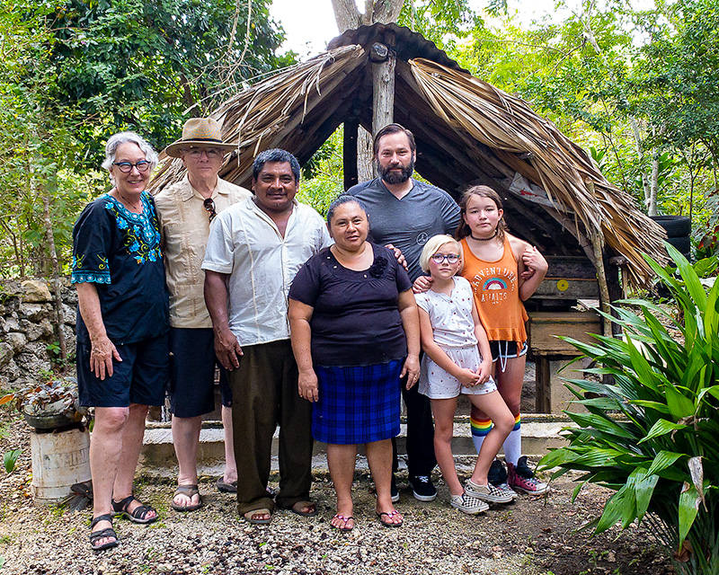 Group photo of Maya beekeepers and visitors in front of a traditional Melipona hut