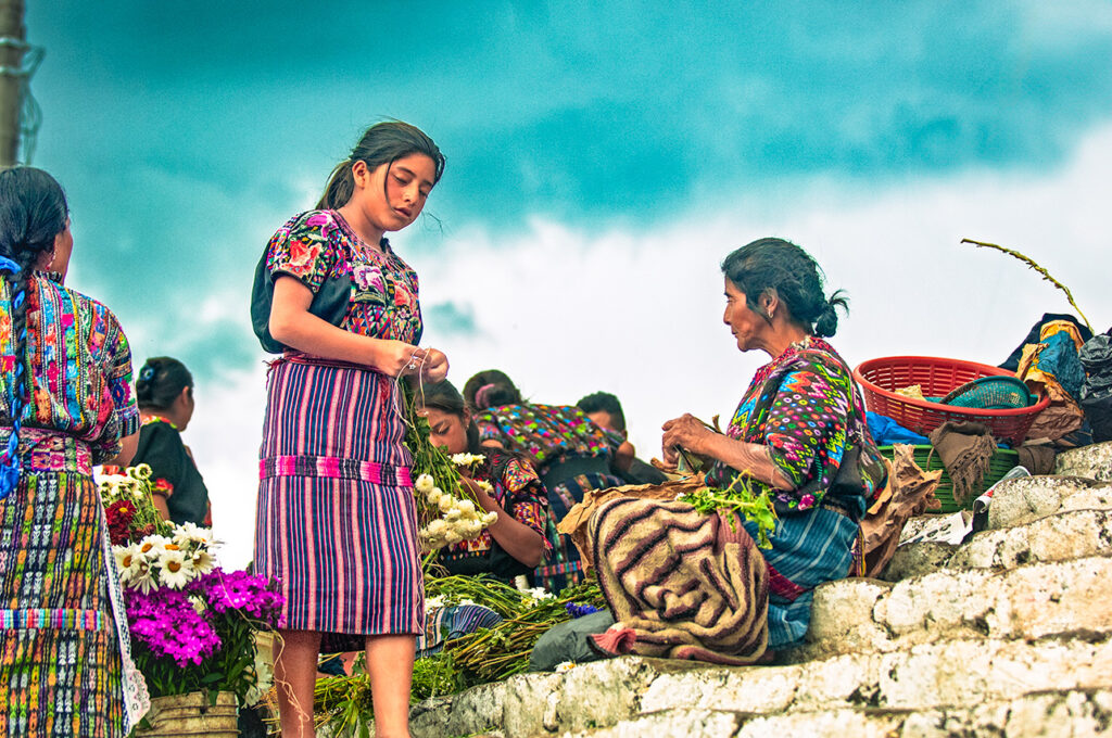 Maya women in traditional dress selling flowers at a market