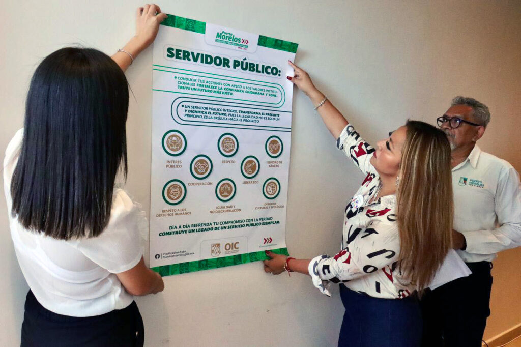 Municipal staff hang a poster outlining public servant ethics guidelines