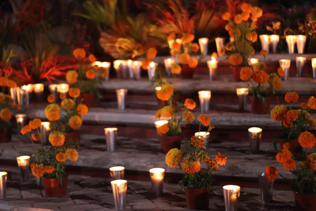 Staircase decorated with glowing candles and orange cempasúchil flowers at night.