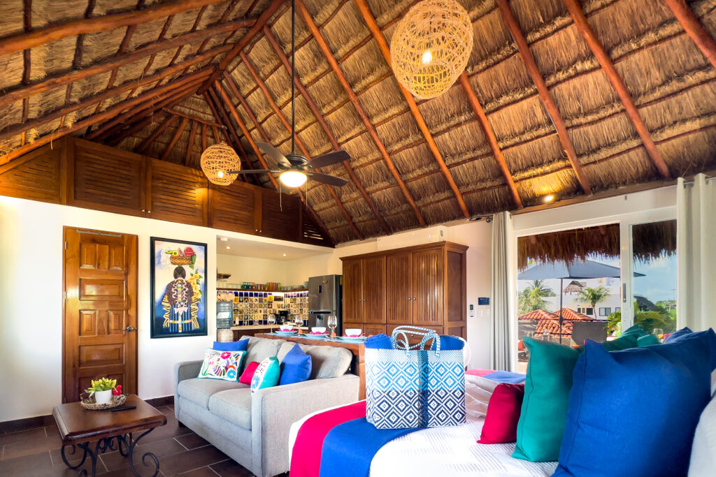 Bright open studio with palapa ceiling, sofa, king bed, and kitchen area at Casa Catalina #3 in Puerto Morelos.
