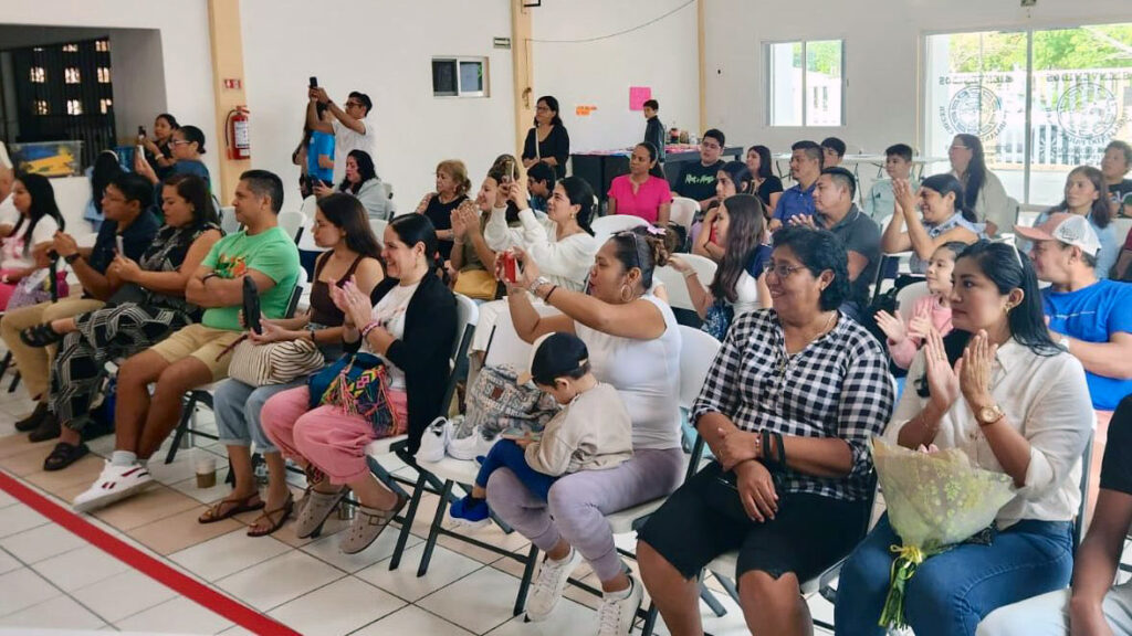 Families and spectators applaud during a gymnastics event in a community hall in Puerto Morelos.