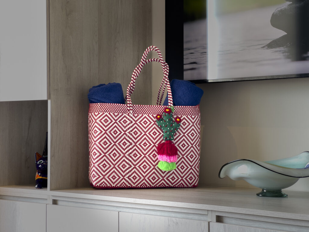 Colorful beach bag with towels displayed on a built-in shelf in a modern studio.
