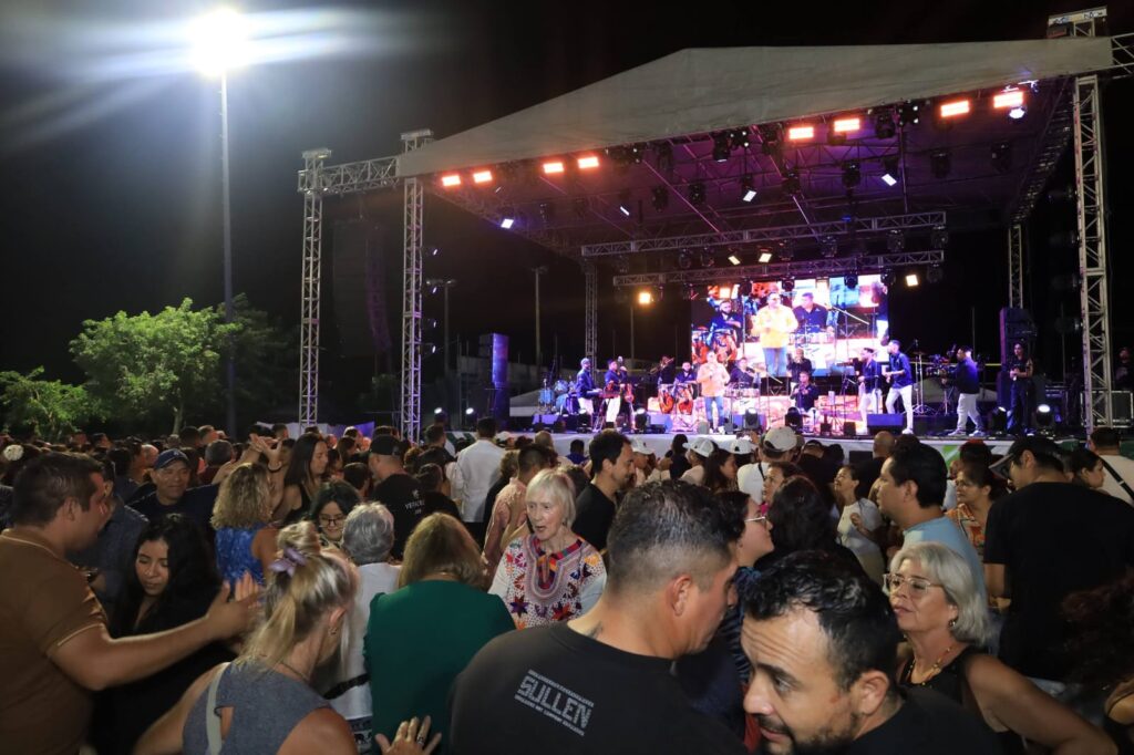 Crowd watches an outdoor concert stage at night during Puerto Morelos anniversary event.