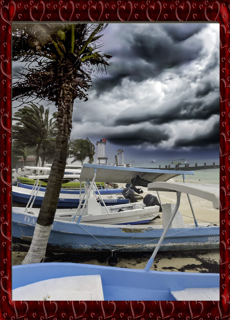Palm tree and small boats on Puerto Morelos beach under dramatic storm clouds over turquoise water.