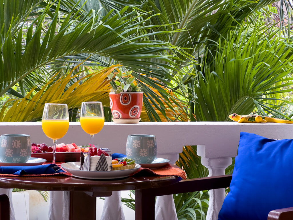 Breakfast table set on a balcony with palm trees in the background.