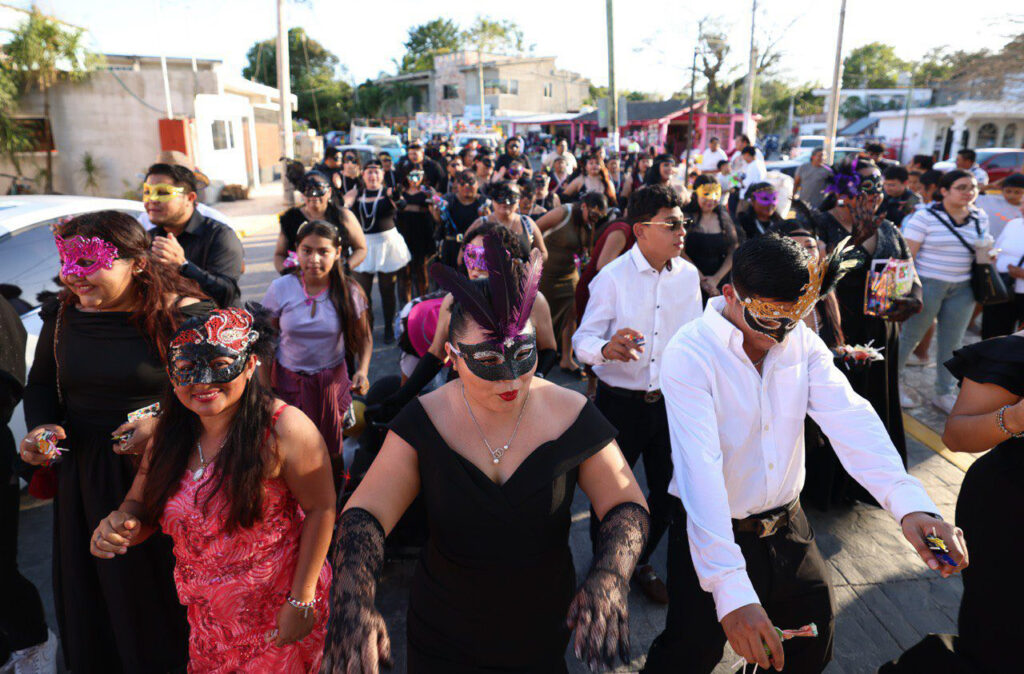 Crowd in masks and black outfits marches together during the Carnival parade.
