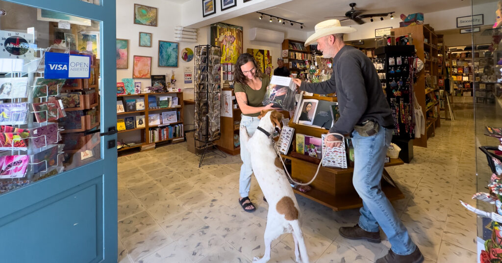 Michael A. Maurus greets a guest at Alma Libre Bookstore in Puerto Morelos during a book signing, with Bruno standing between them.