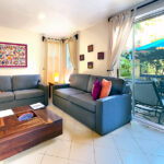 Living room with two sofas, wooden coffee table, and sliding glass doors opening to a private patio.