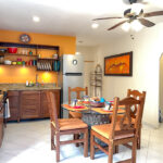 Dining table and full kitchen with orange accent wall, ceiling fan, and arched doorway