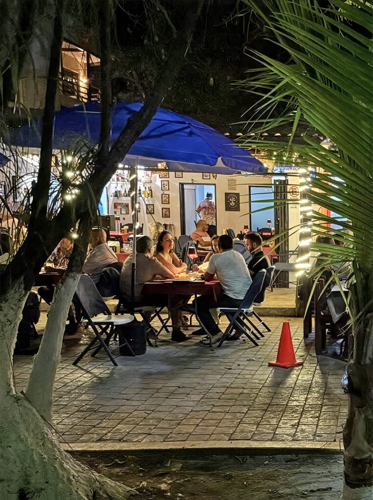 People sit and talk outside a small café in Puerto Morelos during the evening.