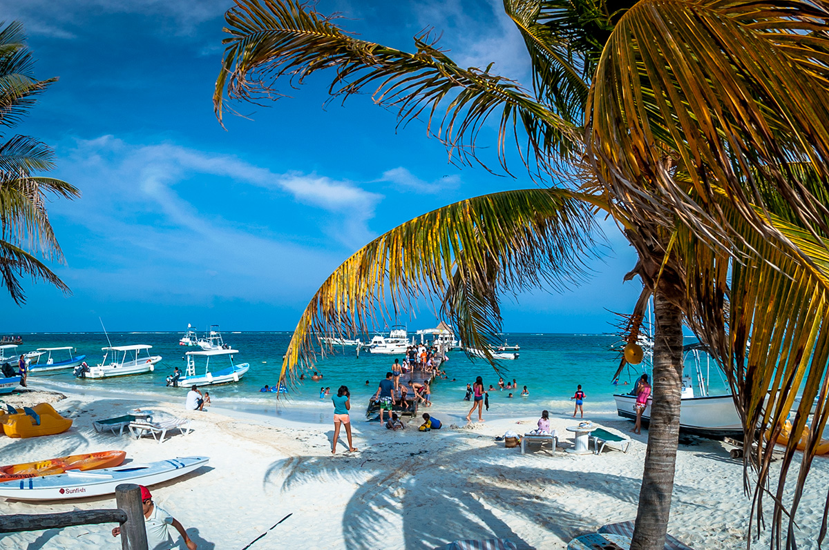 Puerto Morelos beach with swimmers, small boats and palm trees